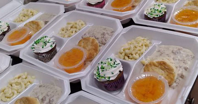 Styrofoam boxes filled with biscuits, pasta, gravy, a fruit cup and a chocolate cupcake