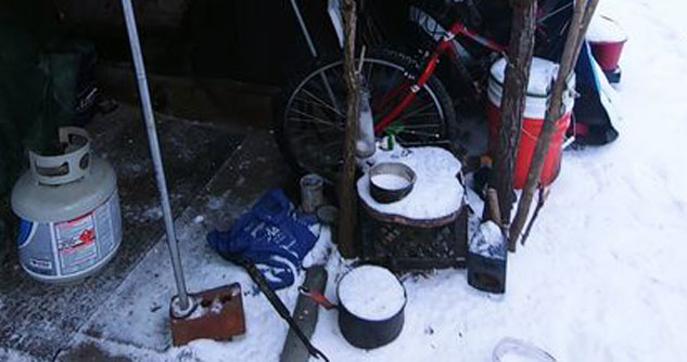 Cardboard on the ground with propane and a bike under a tent