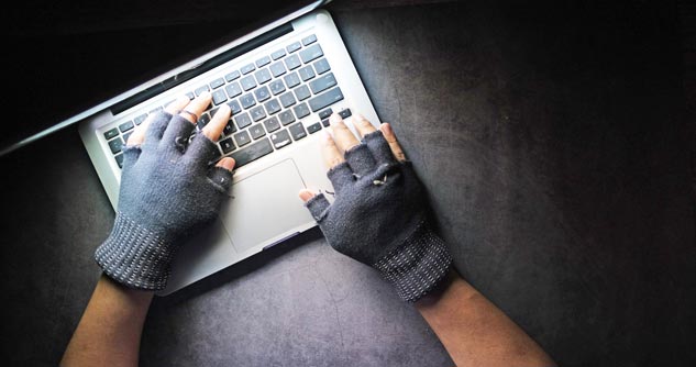 Man wearing gloves tapping on a keyboard in near darkness