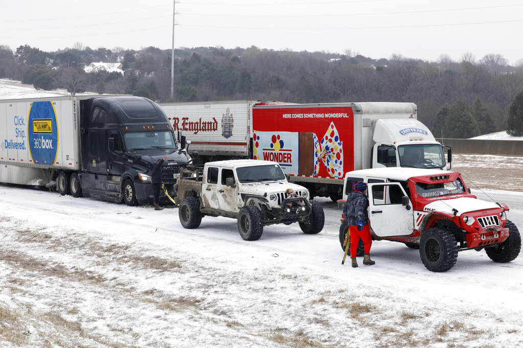Members of the Carnales Off Road Jeep club work to pull a semi-truck up an ice-covered hill on westbound I-20 near Loop 408 in Dallas