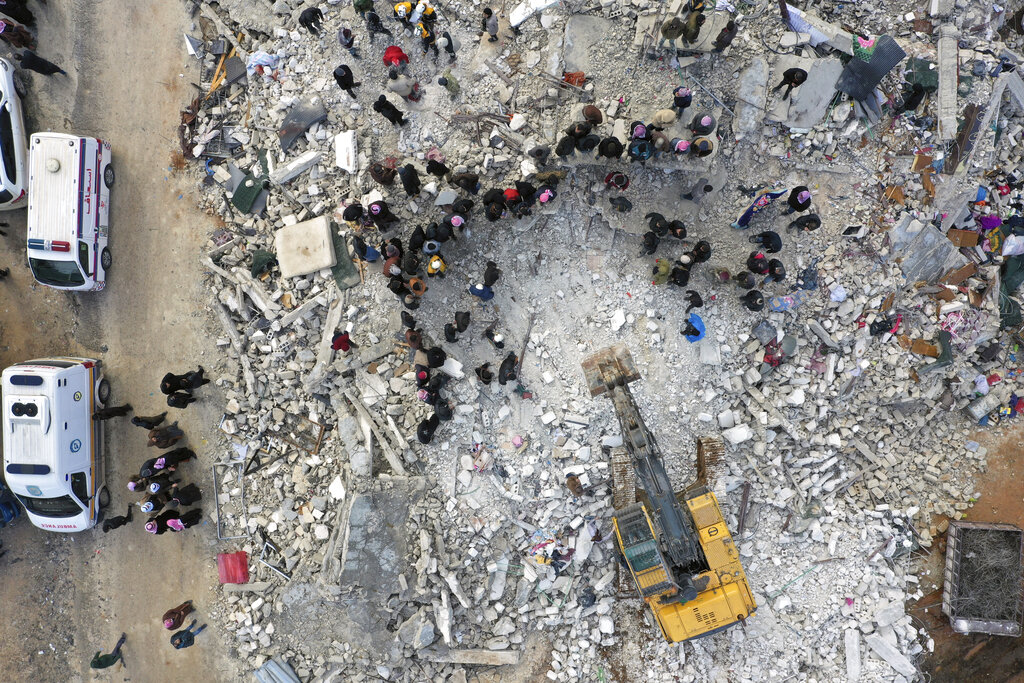 Civil defense workers and residents search through the rubble of collapsed buildings in the town of Harem near the Turkish border, Idlib province, Syria