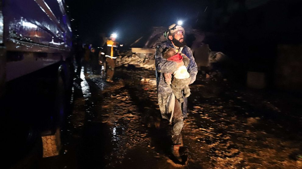 Man in white helmet carrying a baby