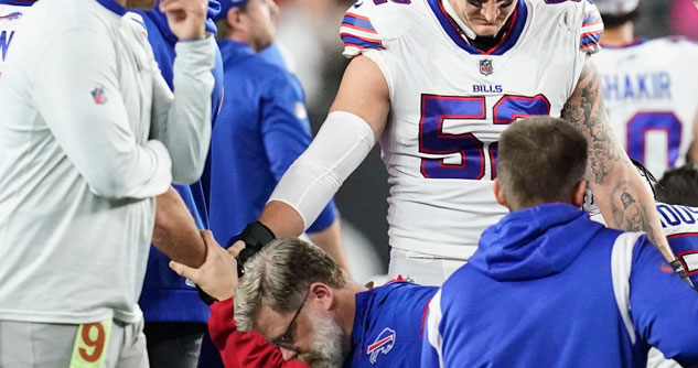 Coach kneeling and holding hands with other Bills