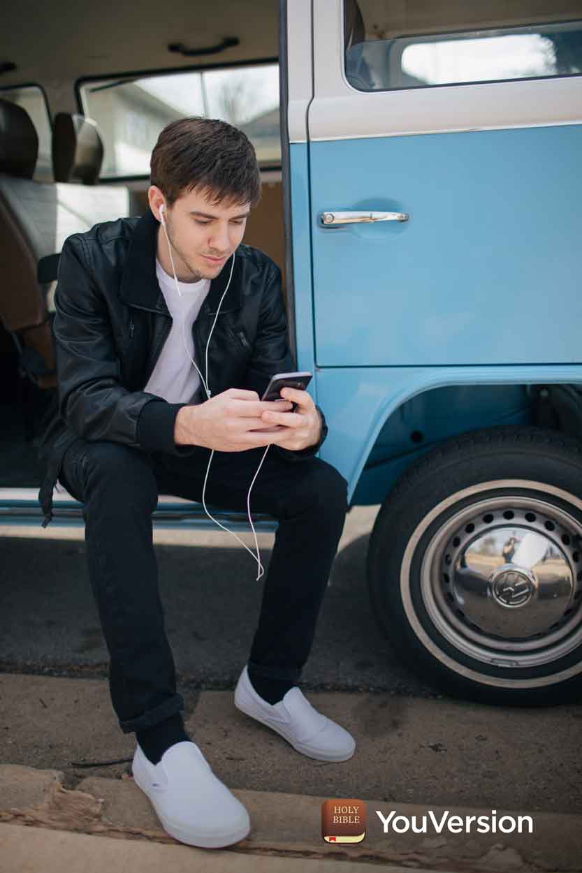 young man studies Bible on phone