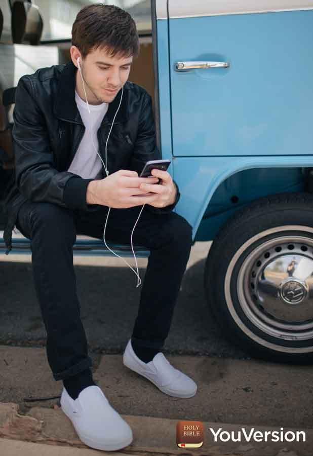 young man studies Bible on phone