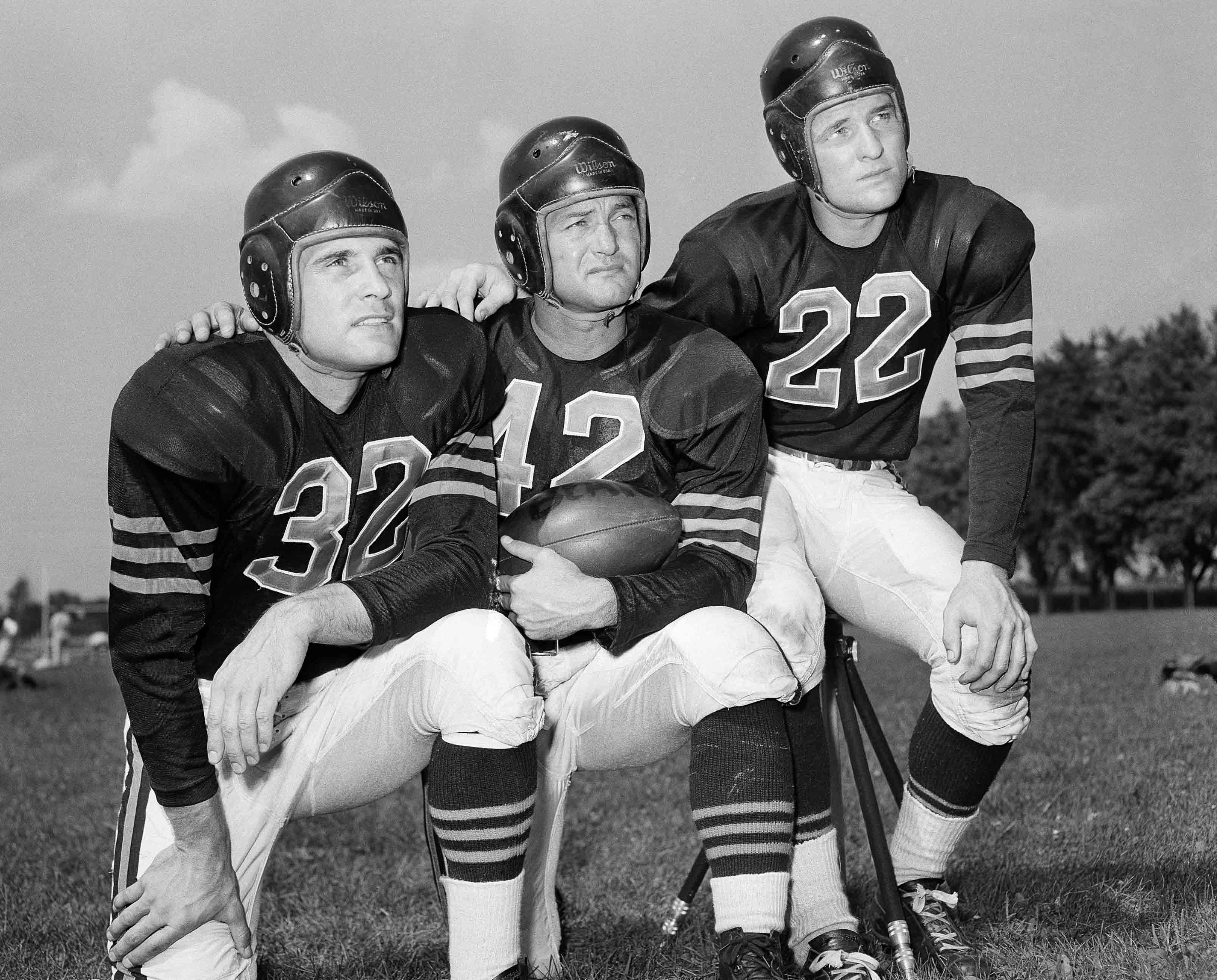 Aug. 25, 1948, file photo, veteran quarterback Sid Luckman, center, poses with two newcomers to the Chicago Bears, Johnny Lujack, left, and, Bobby Layne, during preseason football workouts at Collegeville