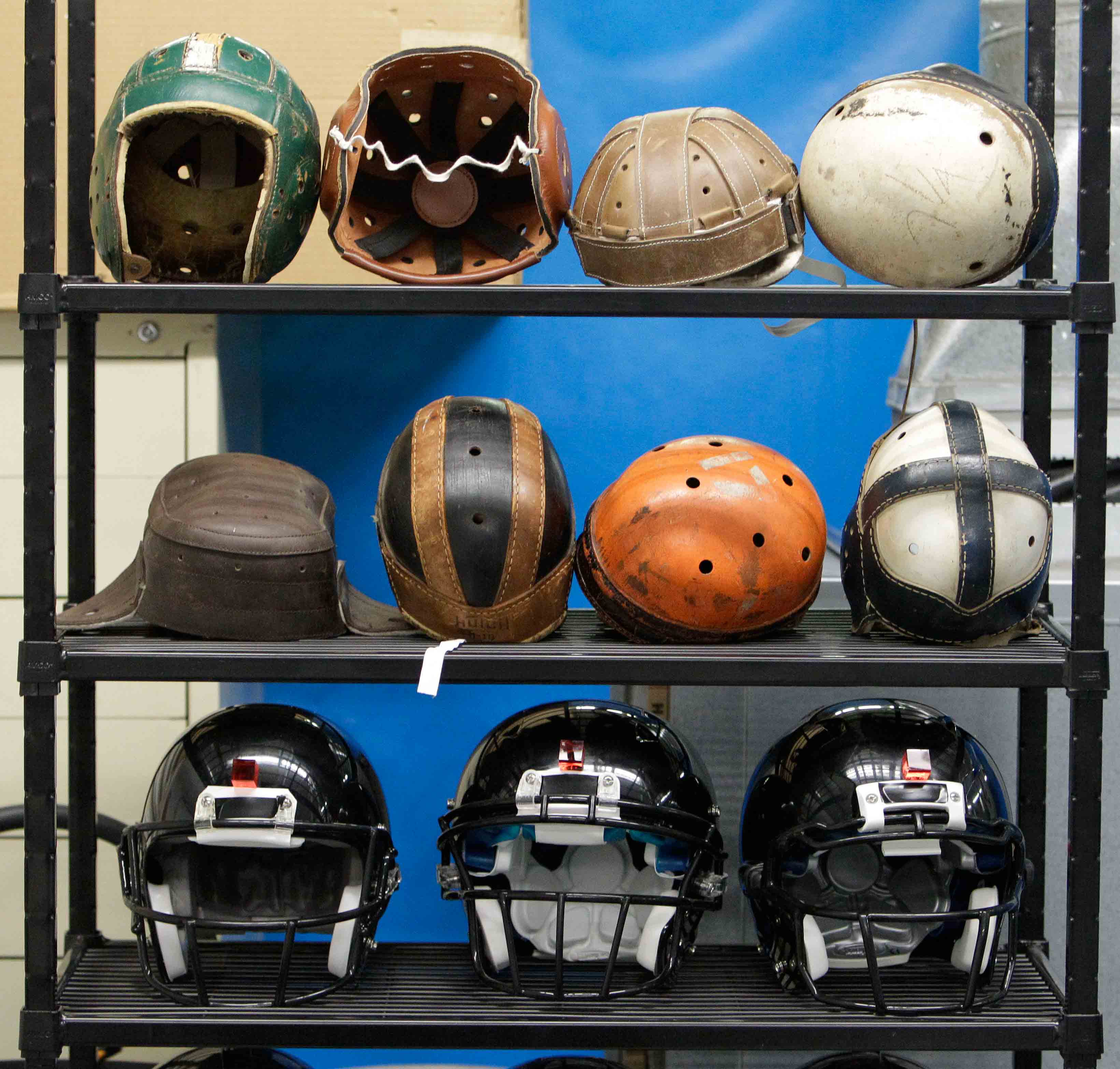 various football helmets, used for testing helmet-to-helmet collisions, are displayed on a rack at a laboratory in the Cleveland Clinic