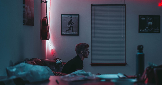 Teen sitting alone in dark bedroom