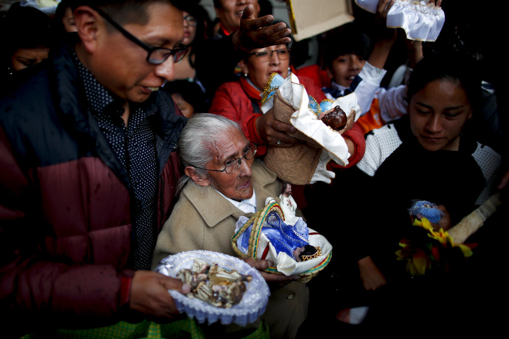 People wait their turn to have their baby Jesus dolls blessed by a priest as they leave the Three Kings Day Mass at San Francisco Church in La Paz, Bolivia. Outside the church, many parishioners went to indigenous guides to get additional blessings that come from the country