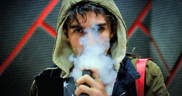 Teen boy in hoodie using vaping pen